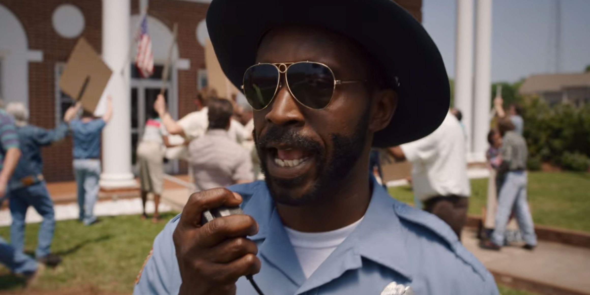 Officer Calvin Powell talks into his radio in front of a protest in Stranger Things