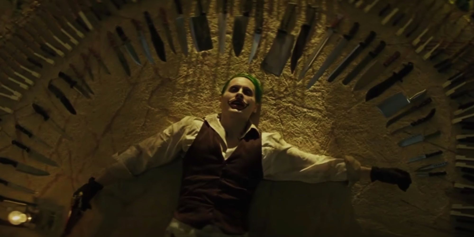 Jared Letos Joker lays surrounded by knives and weapons in Suicide Squad