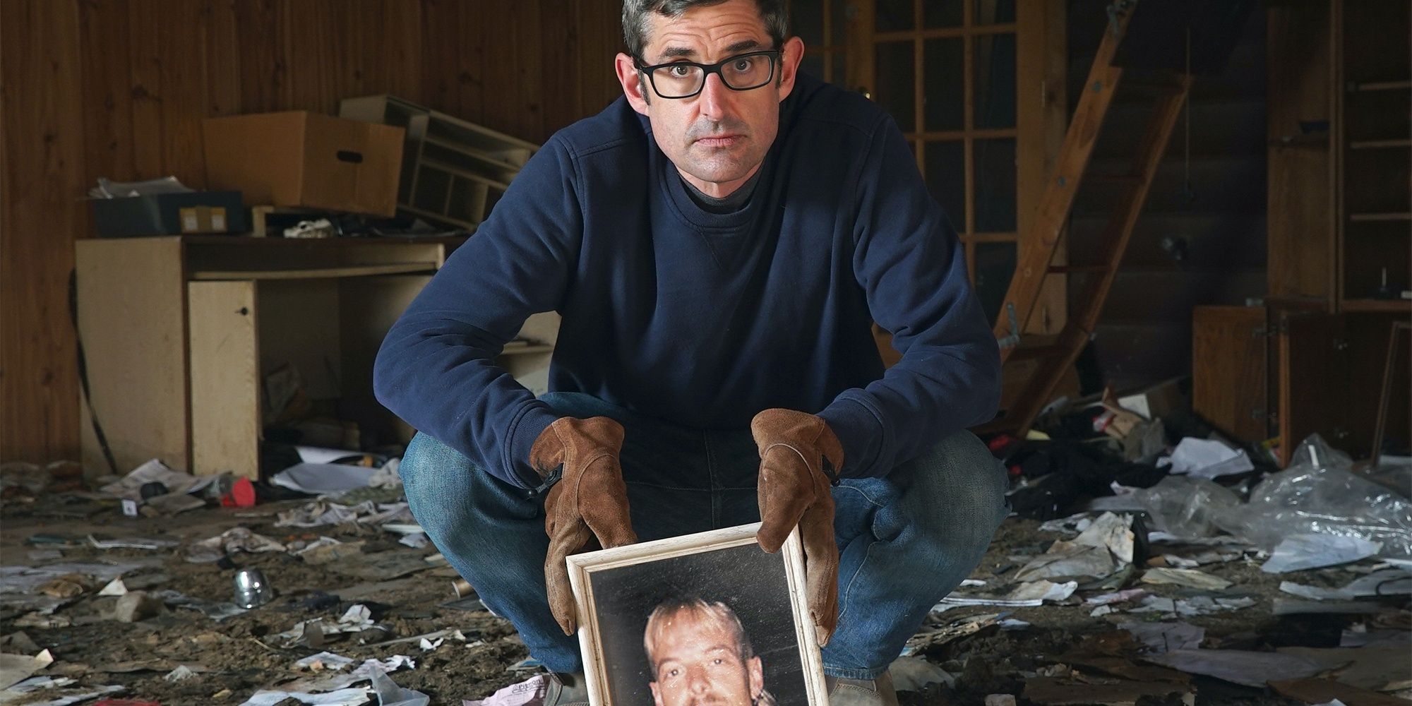 Louis Theroux sitting on his haunches with a photo of Joe Exotic Cropped