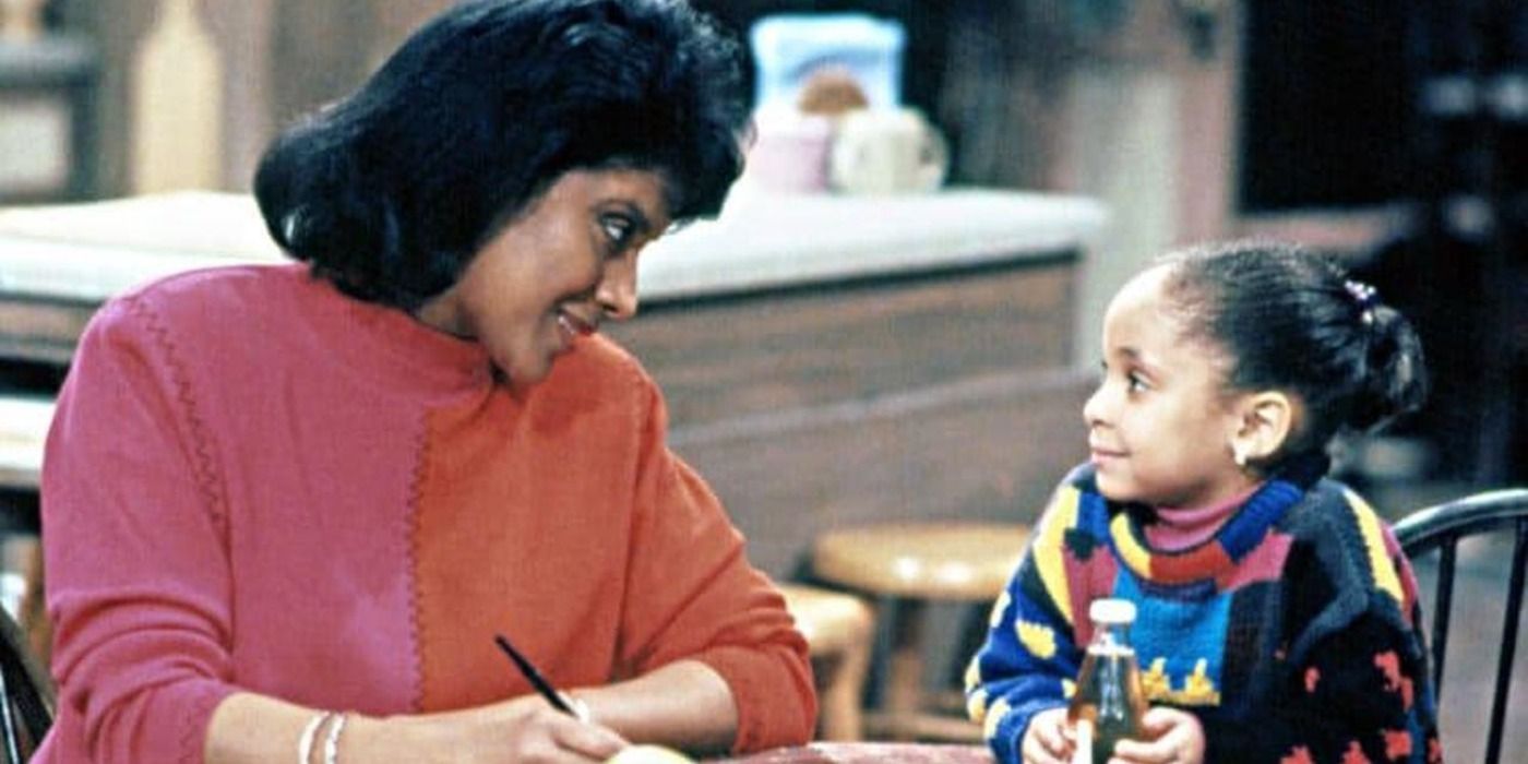 Olivia Kendall sits at a table in the Cosby Show